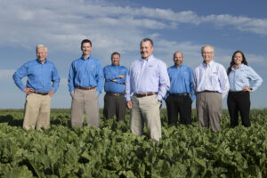 Group of 8 bankers dressed casually standing in a sugar beet field